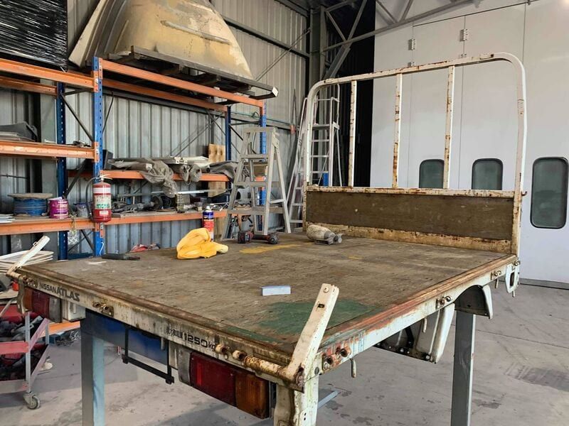 A truck bed is sitting on top of a wooden table in a garage.