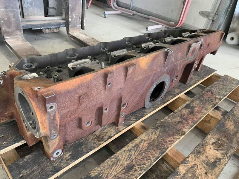 A rusty piece of metal is sitting on top of a wooden pallet.