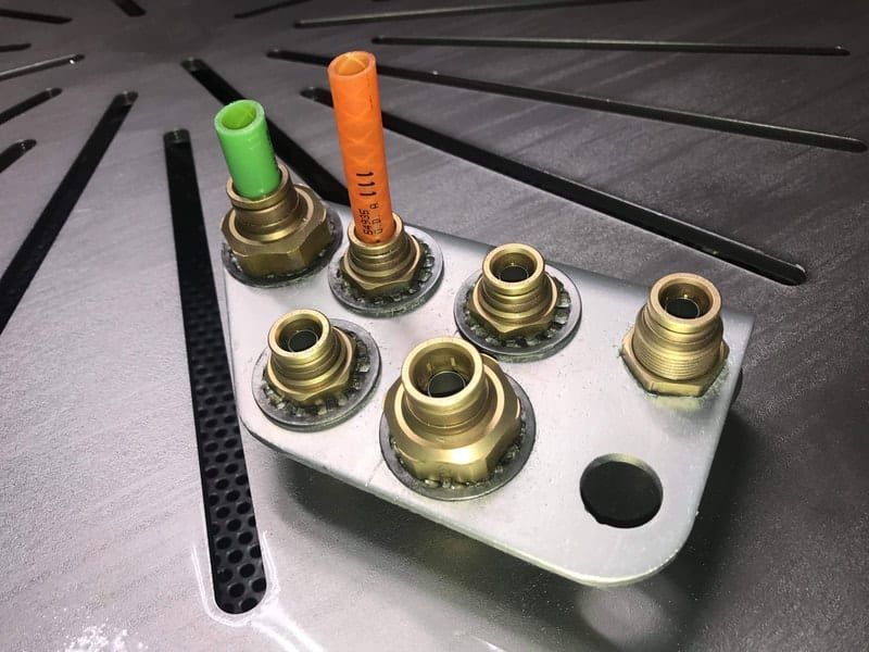 A piece of metal with brass fittings and a green tube that says 111 on it