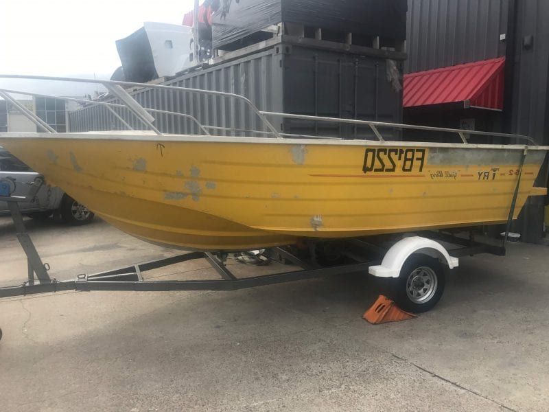 a yellow boat on a trailer is parked in front of a building .