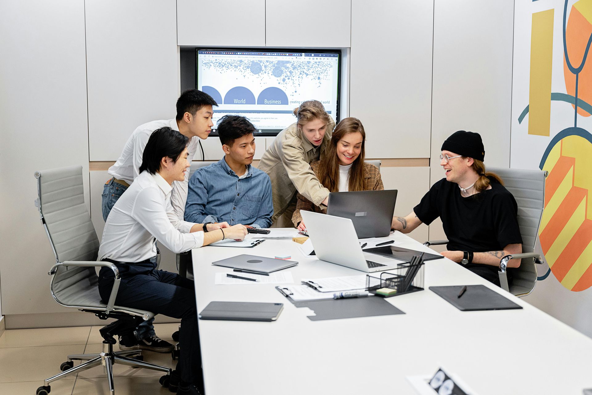Team meeting around a conference table with laptops and papers in a bright office