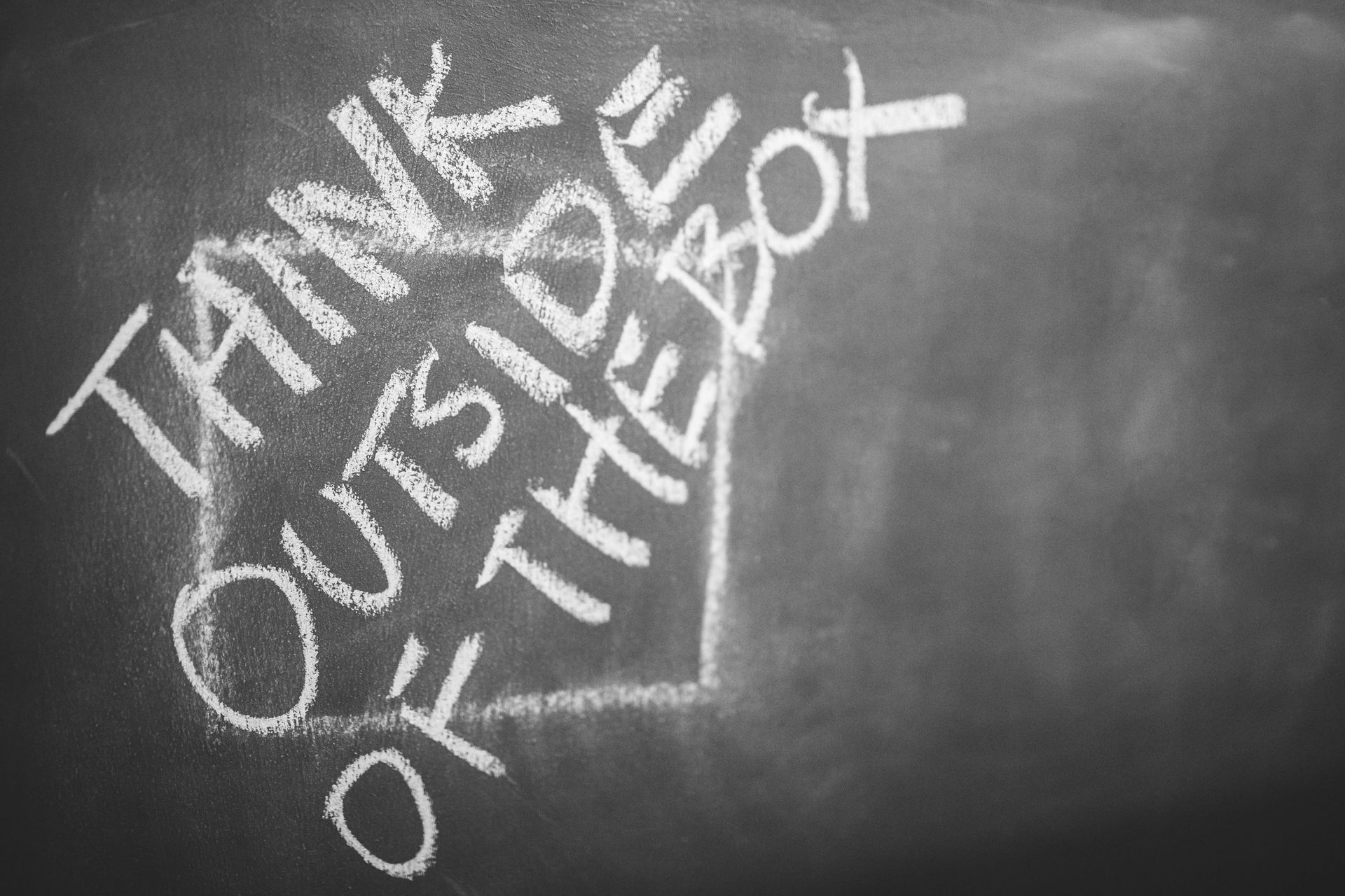 Chalkboard with the words “THINK OUTSIDE OF THE BOX” written in white chalk.