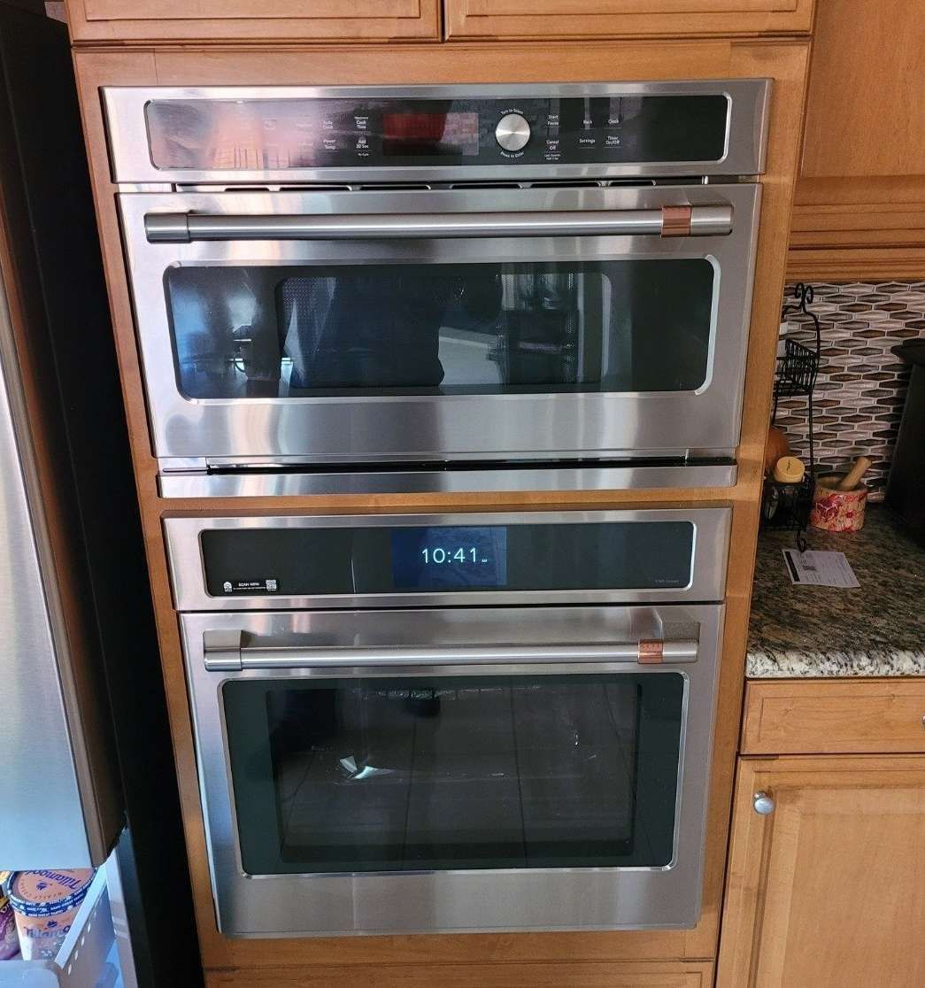 Three stainless steel ovens are stacked on top of each other in a kitchen.
