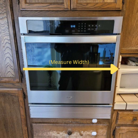 A stainless steel oven with a yellow arrow pointing to the measure width