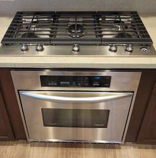 A stainless steel stove top oven is built into a kitchen counter.