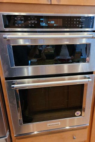 A stainless steel oven is sitting on top of a wooden cabinet in a kitchen.