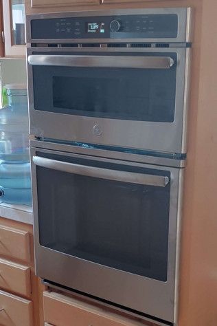 A stainless steel double oven is sitting on top of a wooden cabinet in a kitchen.