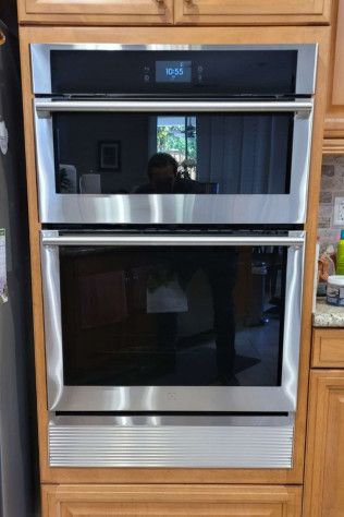 A stainless steel double oven is sitting on top of a wooden cabinet in a kitchen.
