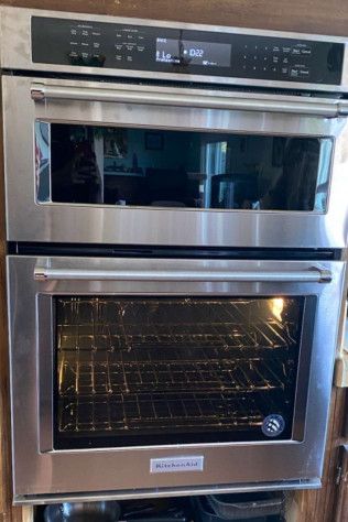 A stainless steel double oven is sitting on top of a wooden cabinet.