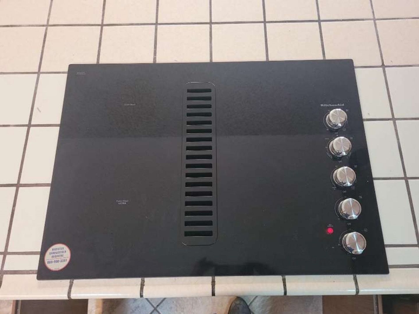 A black stove top is sitting on a tiled counter top