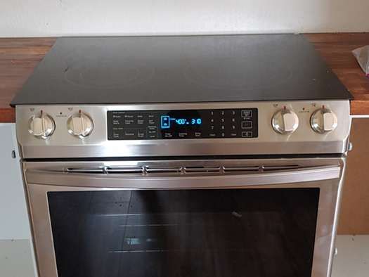 A stainless steel oven is sitting on top of a wooden counter.