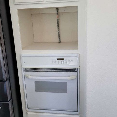 A white oven is built into a cabinet in a kitchen.