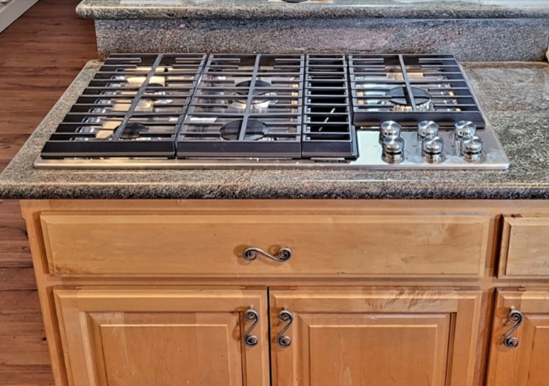 A stove top oven is sitting on top of a granite counter in a kitchen.