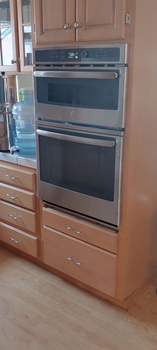A kitchen with stainless steel ovens and wooden cabinets.