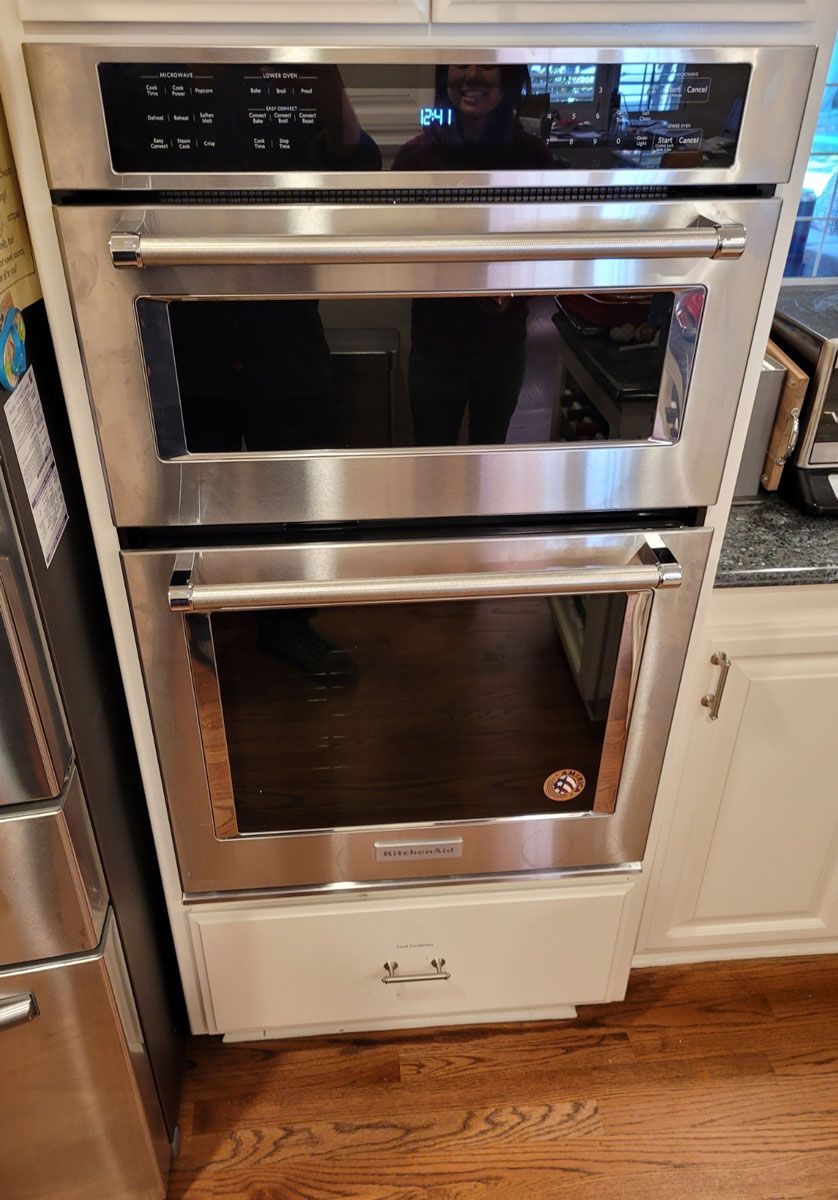 A stainless steel double oven is sitting in a kitchen next to a refrigerator.