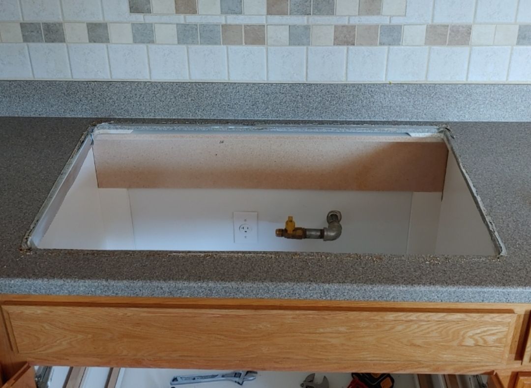 A kitchen sink with a wooden cabinet underneath it