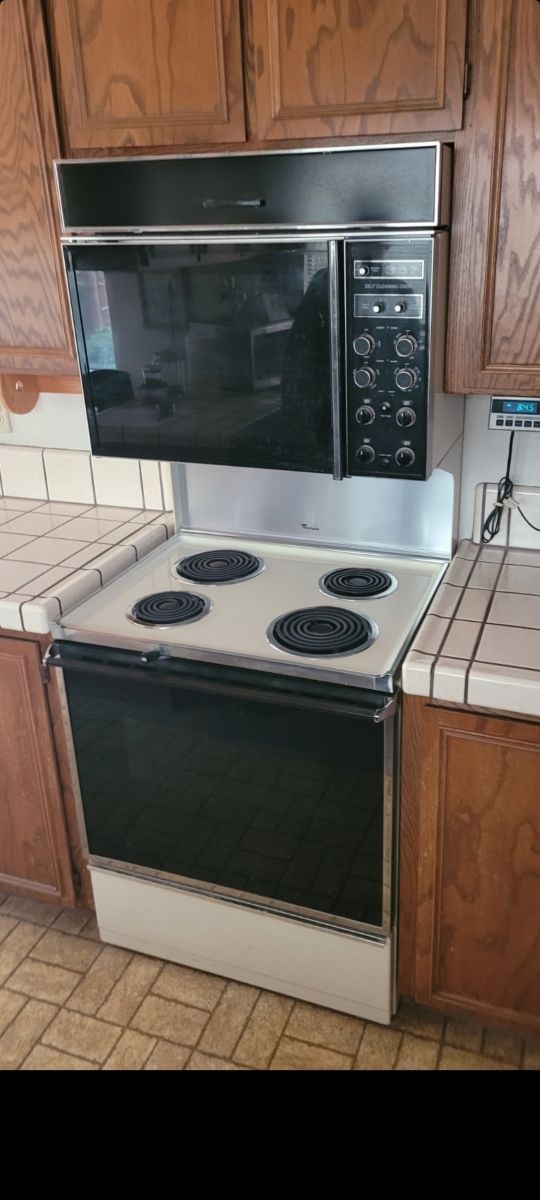 A stove with a microwave above it in a kitchen.
