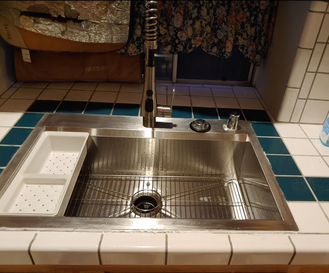 A stainless steel kitchen sink with a drain