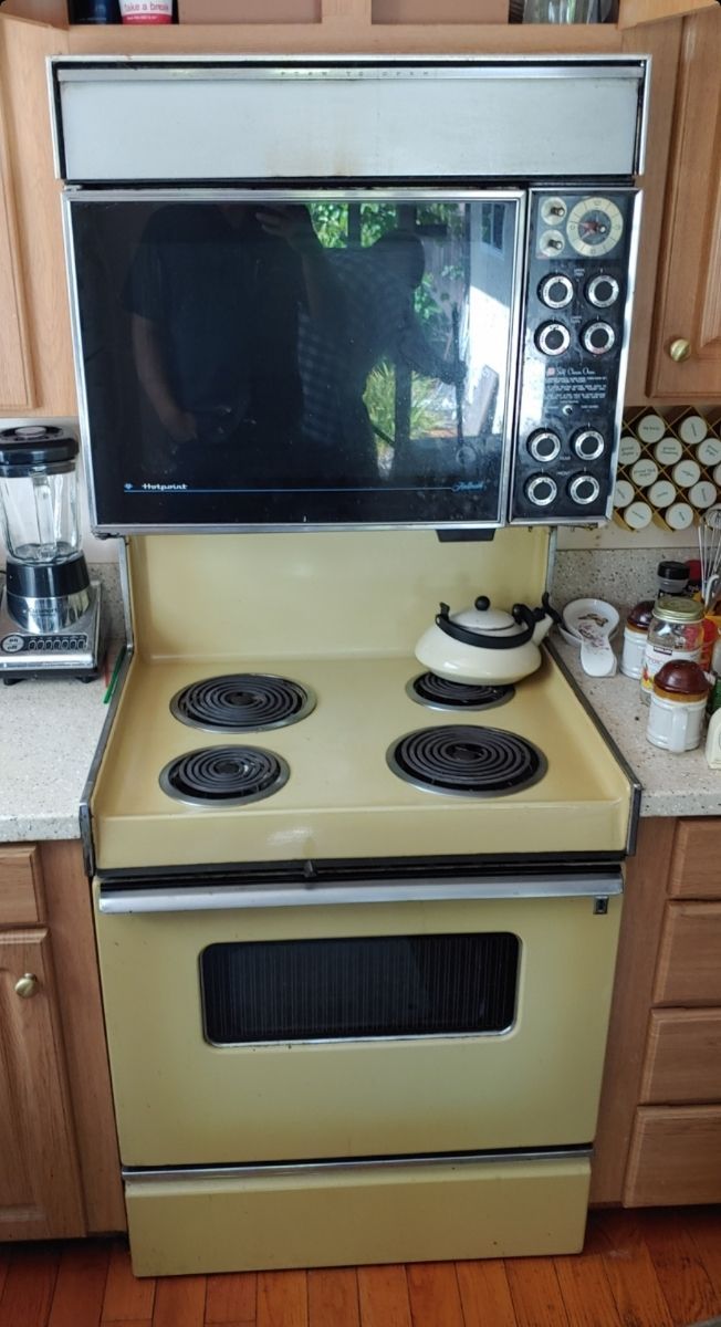 A yellow stove with a microwave above it in a kitchen.