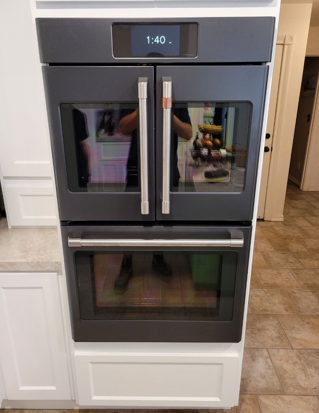 A black double oven is sitting on top of a white cabinet in a kitchen.