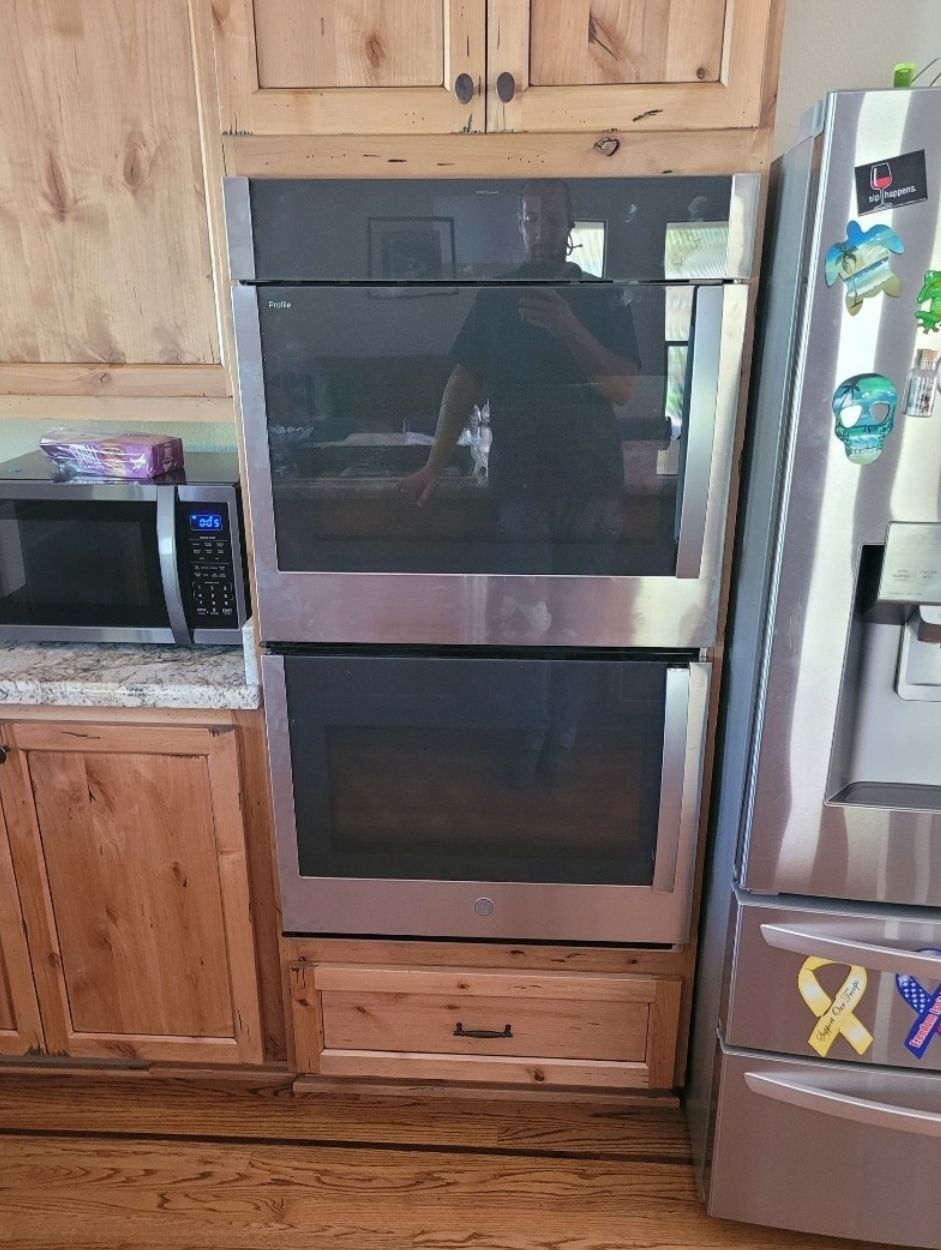 A kitchen with a double oven , microwave and refrigerator.
