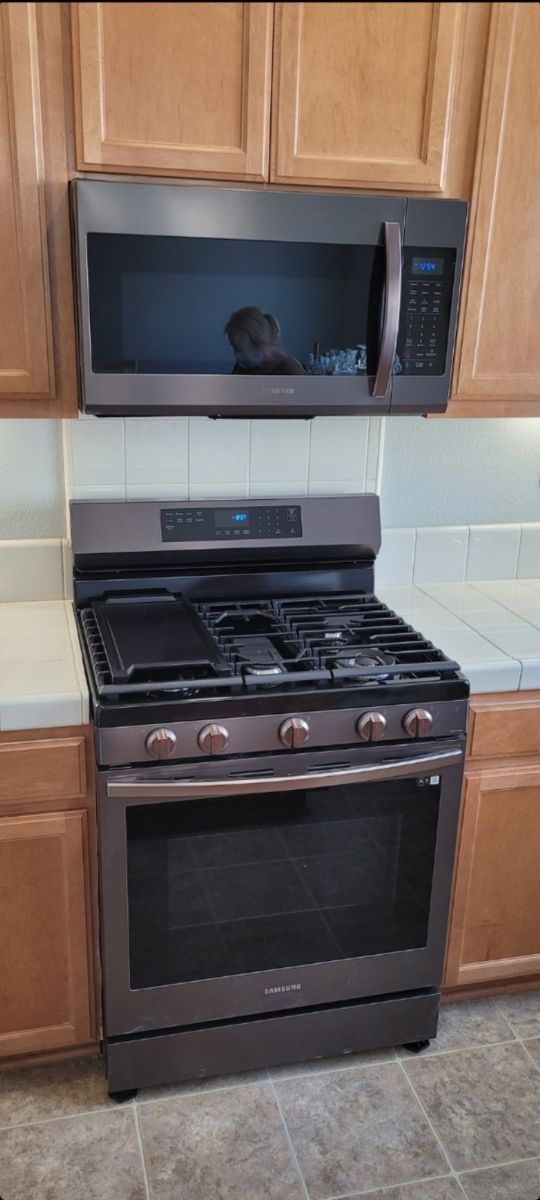 A stove and microwave are in a kitchen with wooden cabinets.