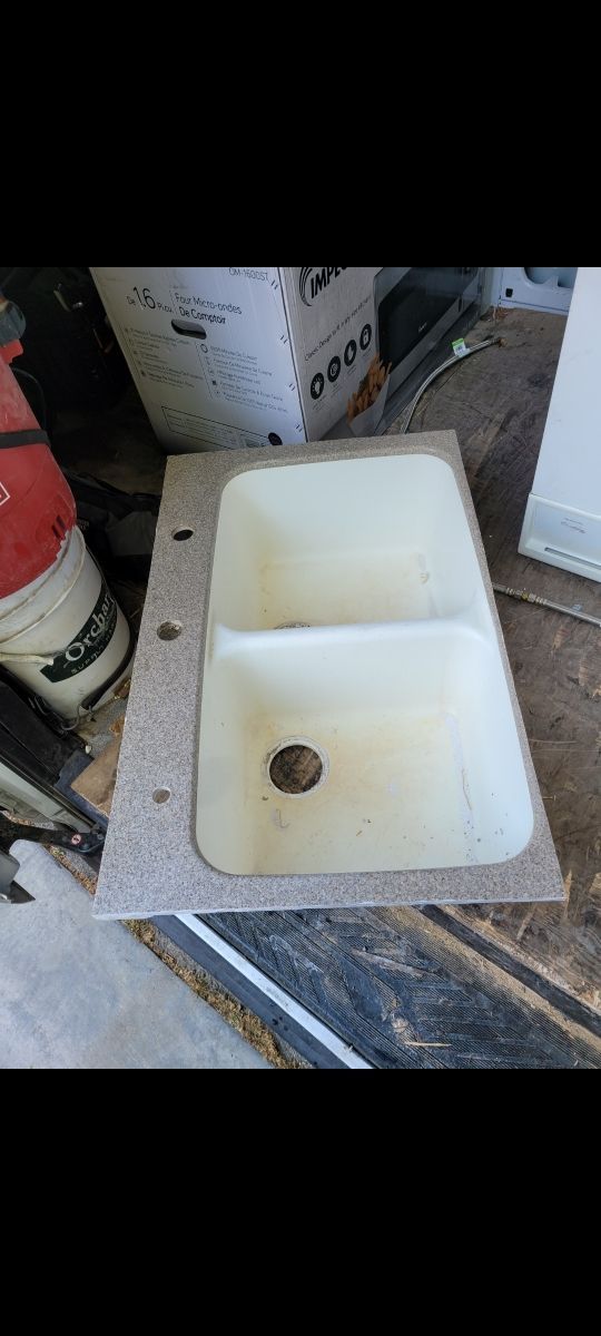 A kitchen sink is sitting on top of a wooden table.