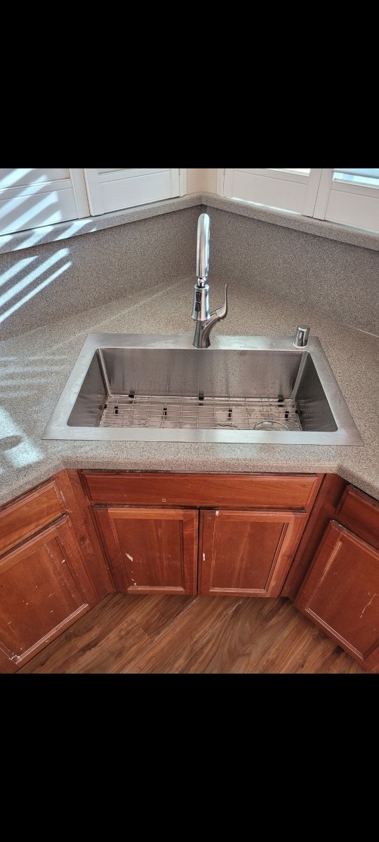 A kitchen sink with a stainless steel faucet and wooden cabinets.