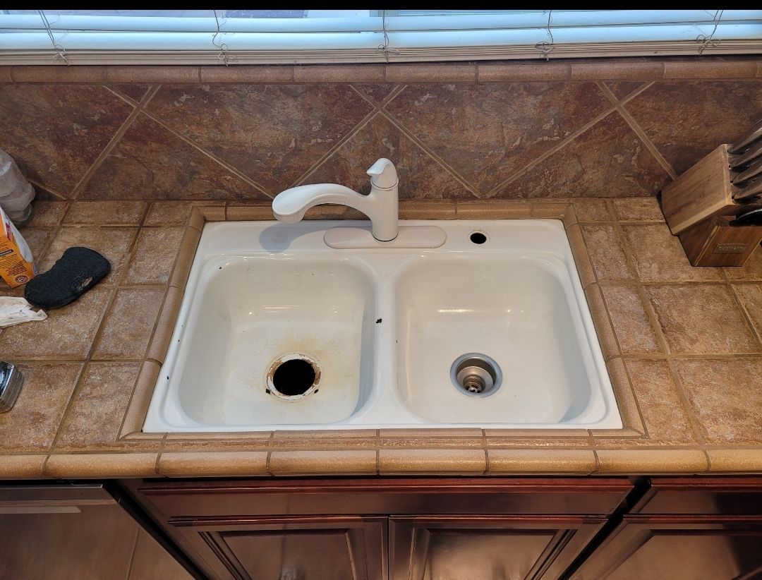 A kitchen sink with two sinks and a faucet on a counter.