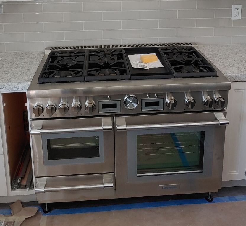 A stainless steel stove with four burners and two ovens