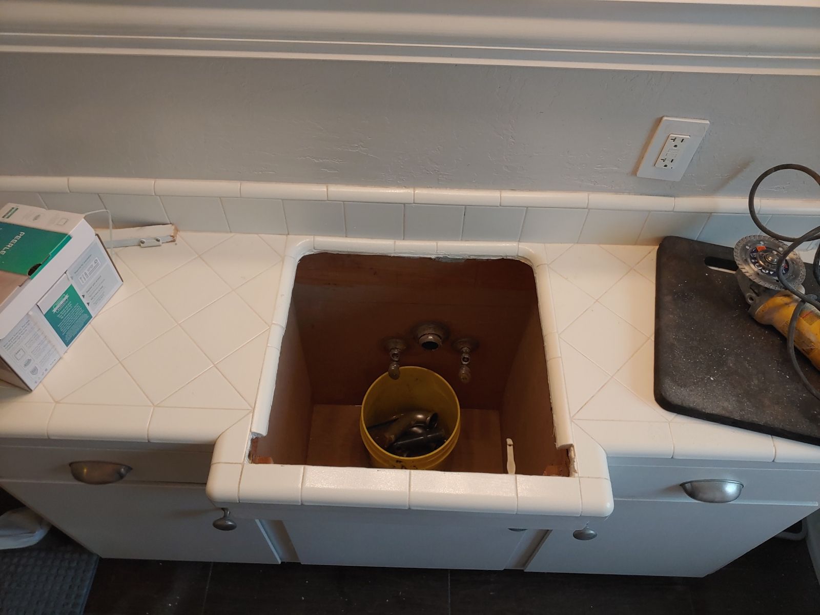 An empty kitchen sink with a yellow bucket in it