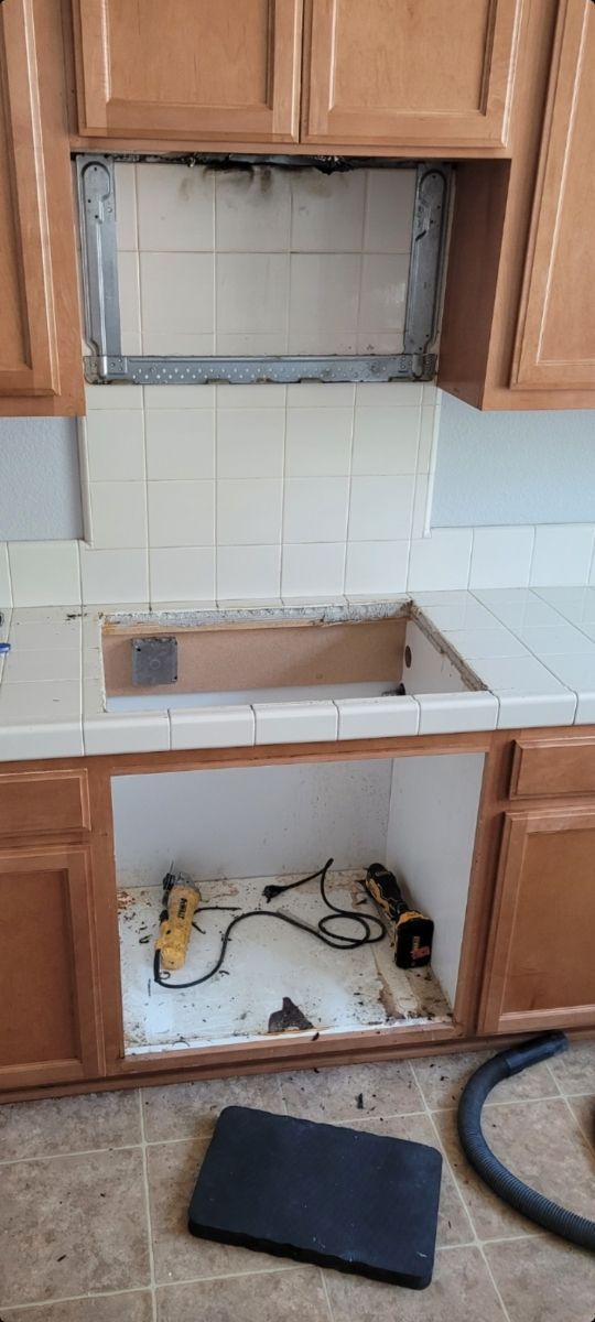 A kitchen sink is being installed in a kitchen with wooden cabinets.
