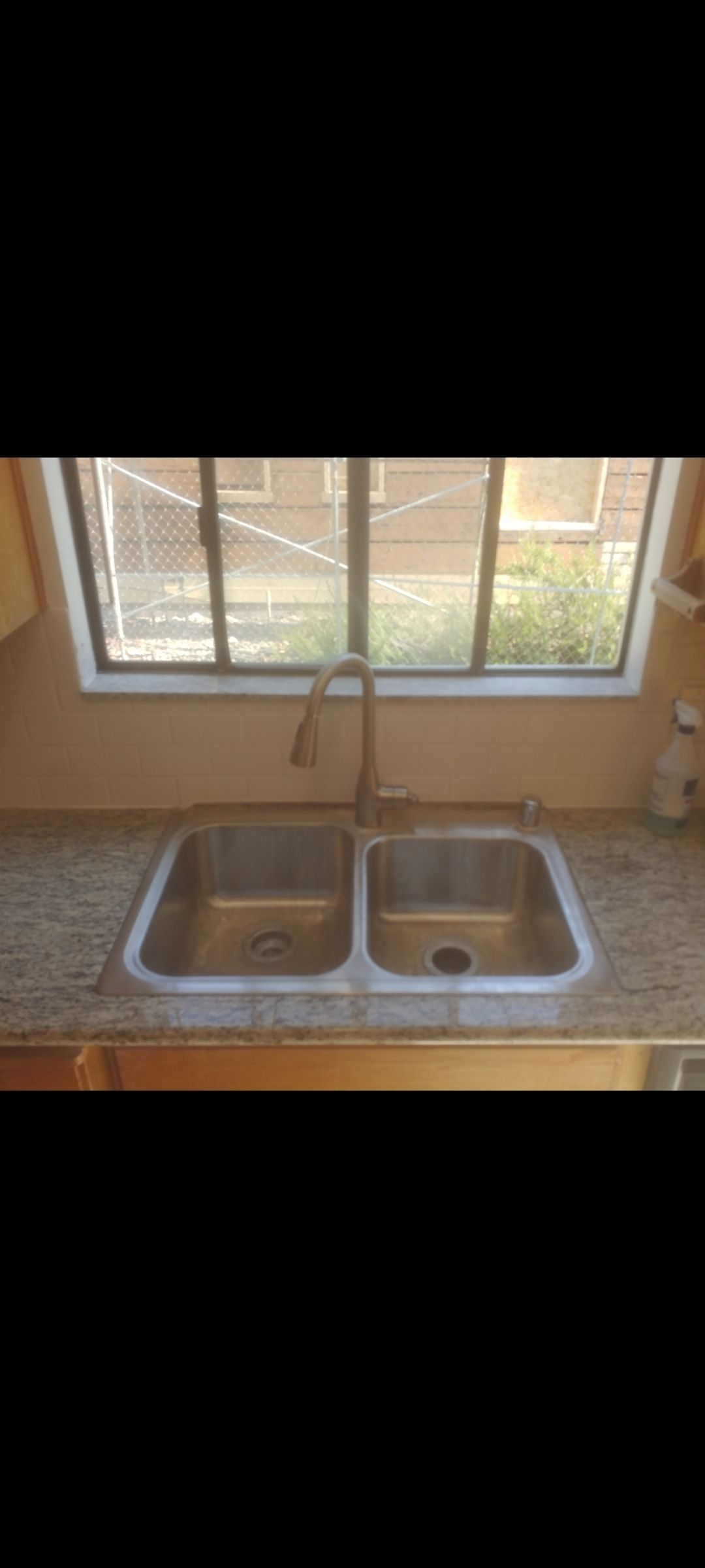 A kitchen sink is sitting under a window in a kitchen.