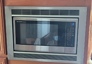 A stainless steel microwave oven is built into a wall in a kitchen.