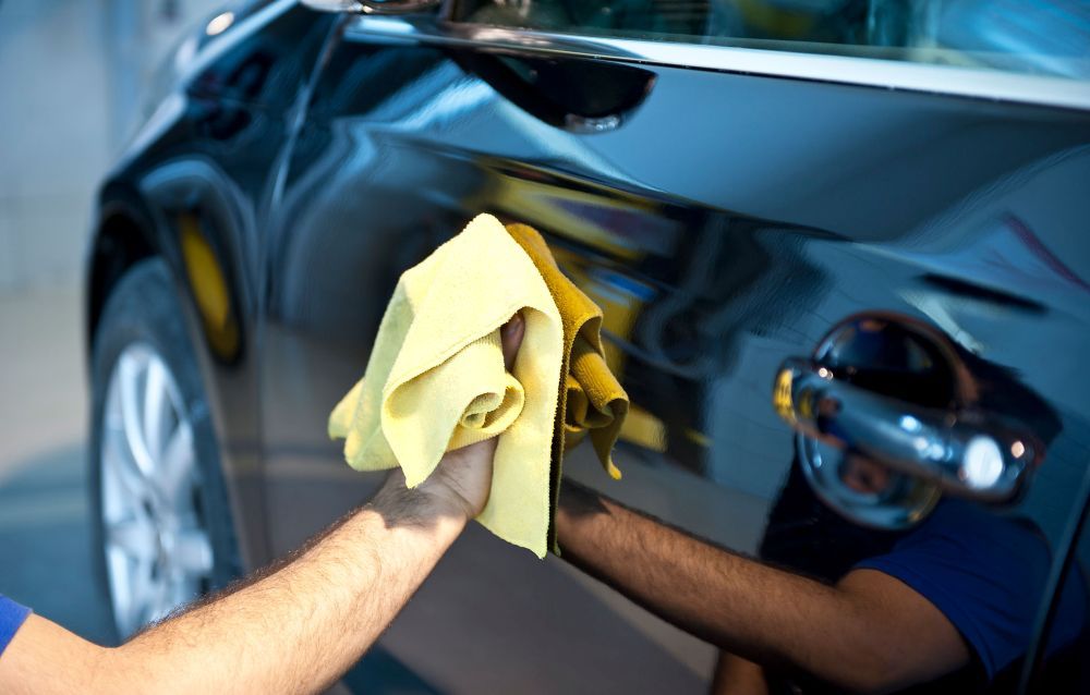 A Man is Cleaning a Car With a Yellow Cloth — Platinum Hand Car Wash & Detailing in Belconnen, ACT