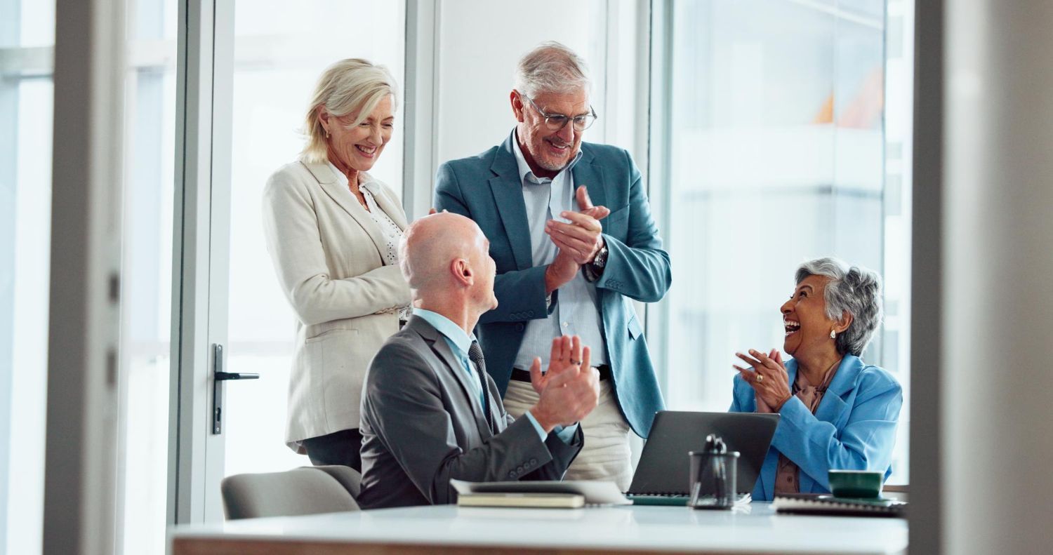Couple signing documents at a table with an advisor in an office setting.