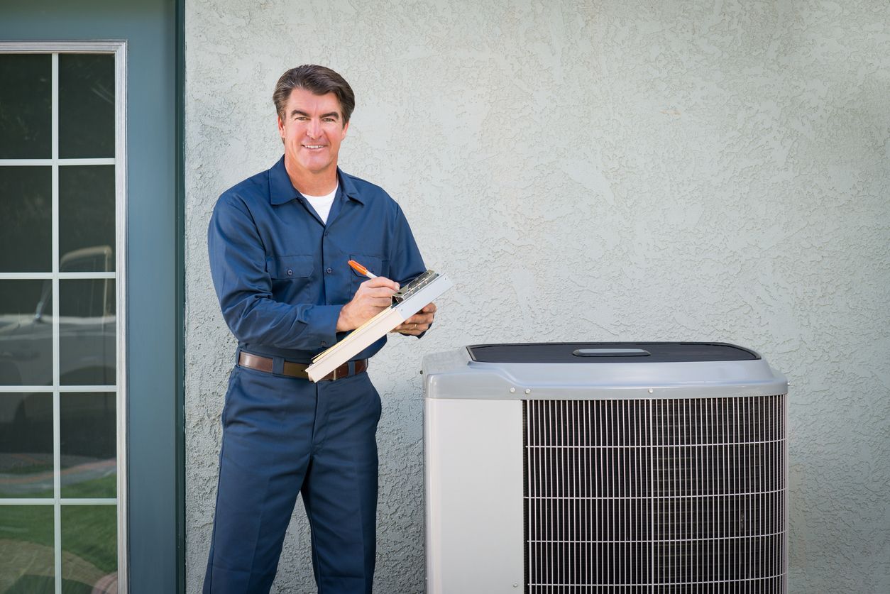 Technician in blue uniform taking notes beside an outdoor air conditioner unit