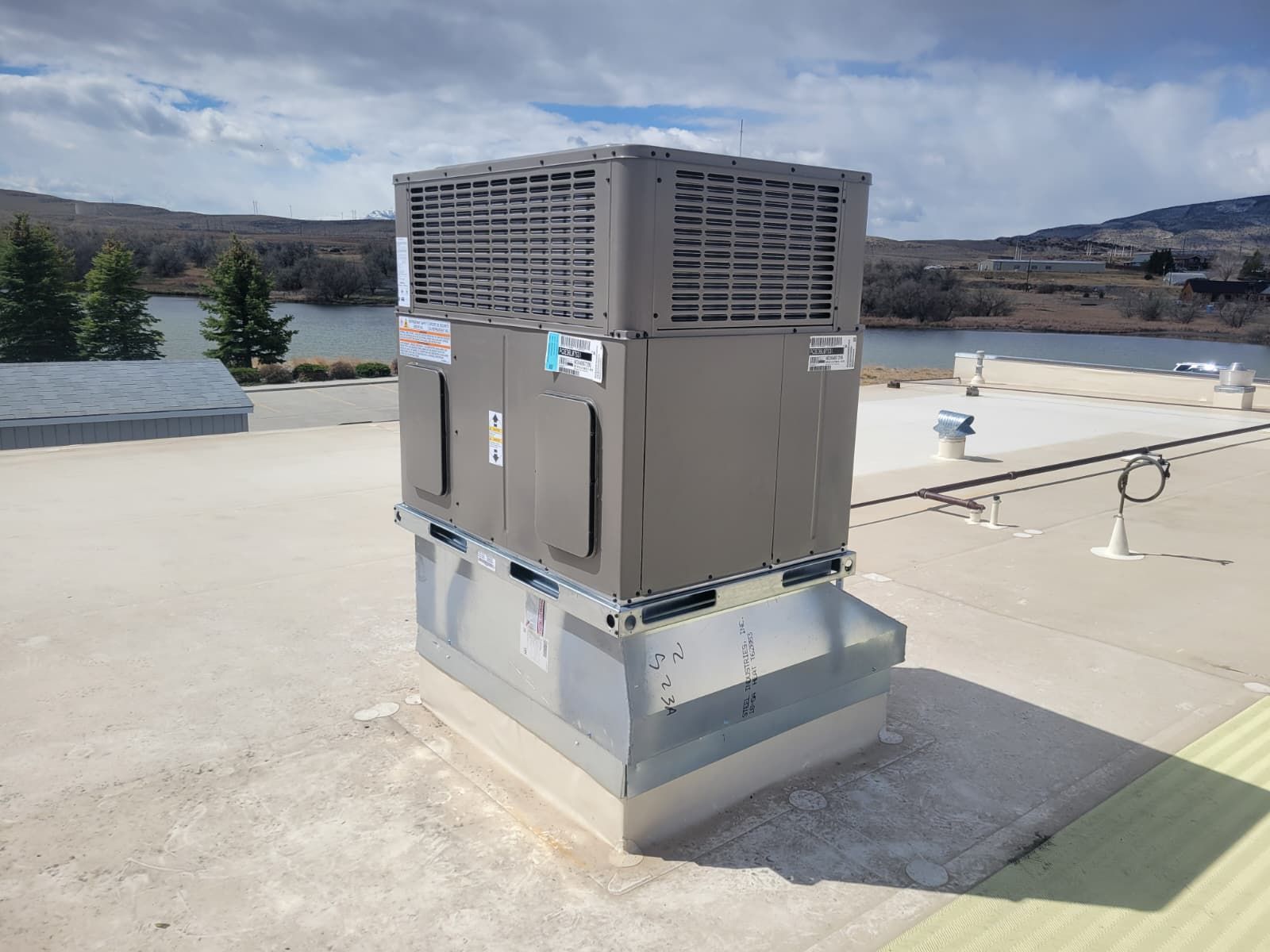 Large rooftop HVAC unit on a flat roof with hills in the background.