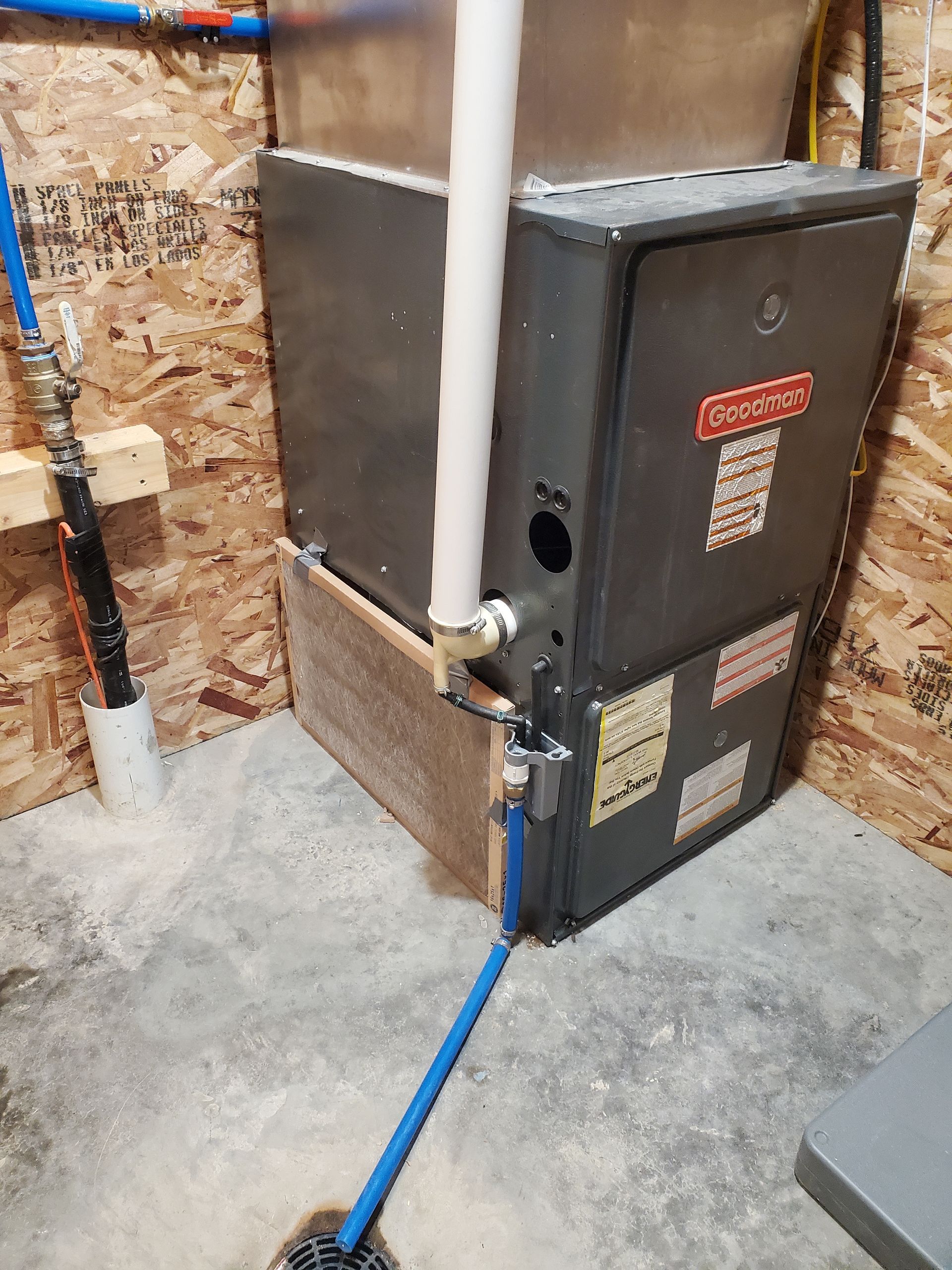 Outdoor electrical service box beside a concrete foundation, with conduit and blue cable connected.