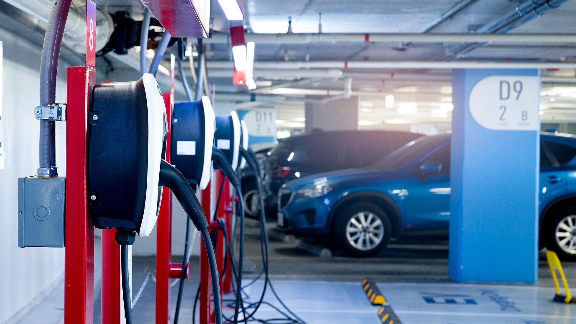 A row of electric cars are being charged in a parking garage.