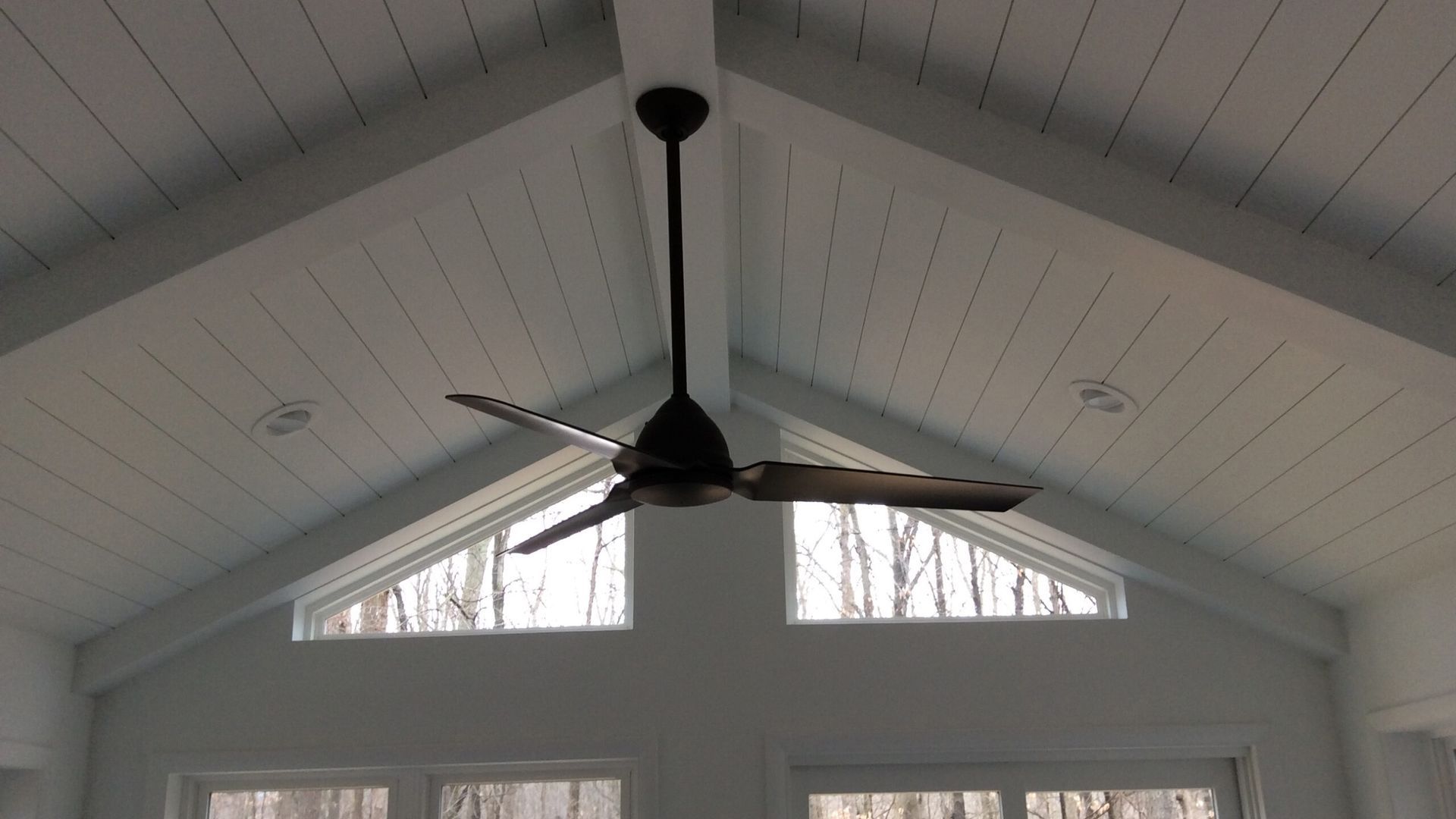 A ceiling fan is hanging from the ceiling of a room with a vaulted ceiling.