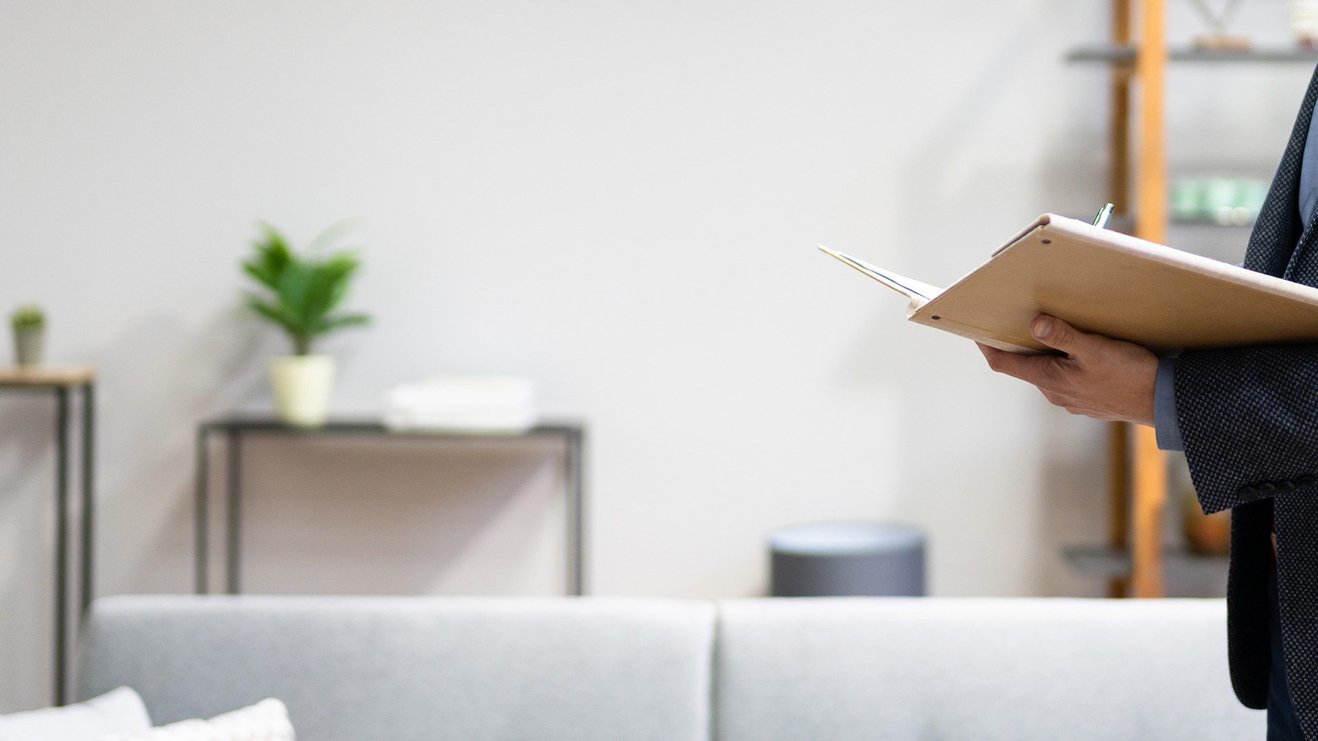 A man in a suit is holding a clipboard in a living room.