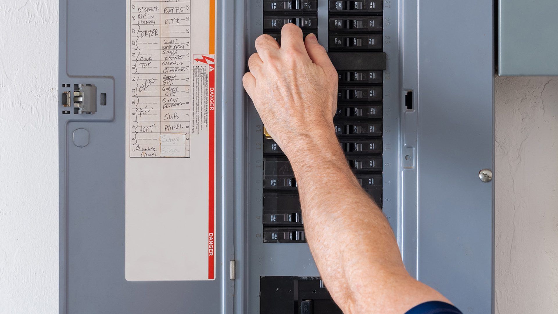 A person is pressing a button on an electrical panel.
