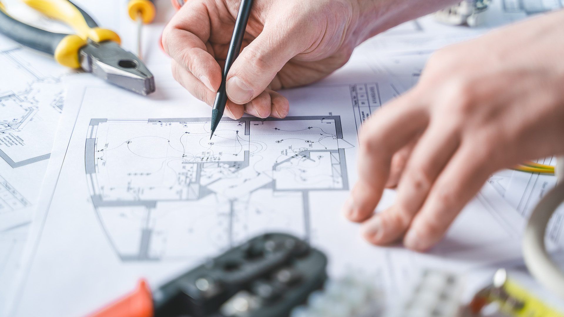 A person is drawing a floor plan of a house on a piece of paper.