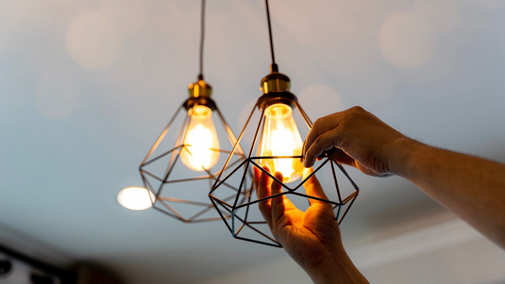 A person is changing a light bulb in a pendant light.
