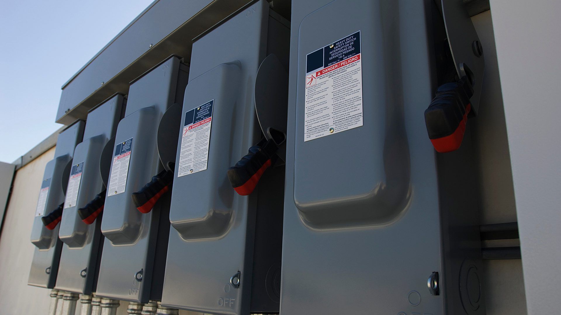 A row of electrical boxes are lined up on a wall.