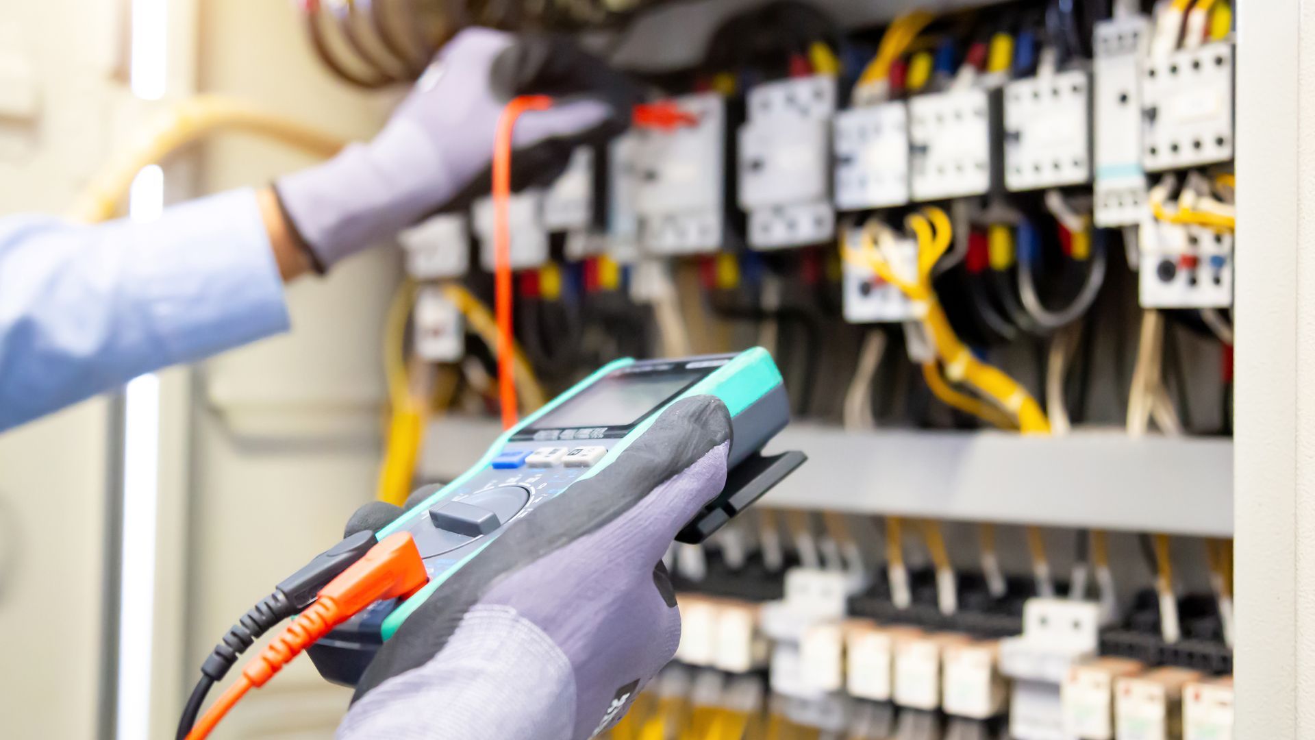 An electrician is using a multimeter to test a circuit board.