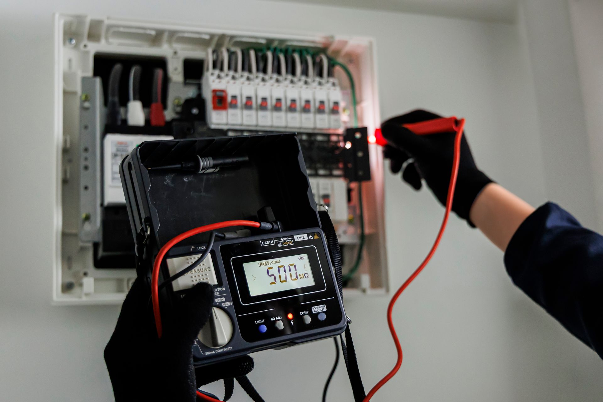 Technician testing an electrical panel with a multimeter and red probe