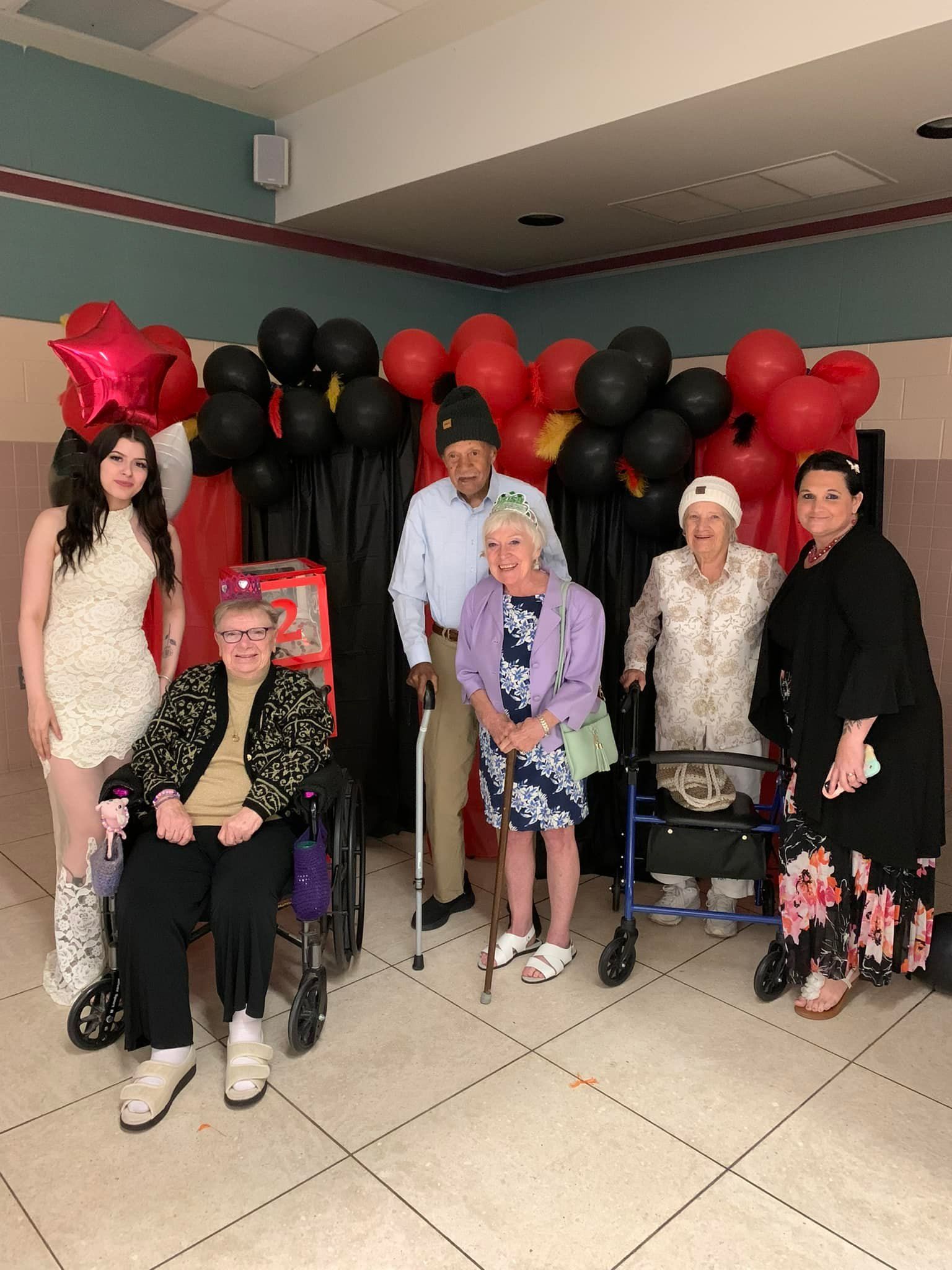 Group of people, including seniors, posing for a photo in front of balloons.