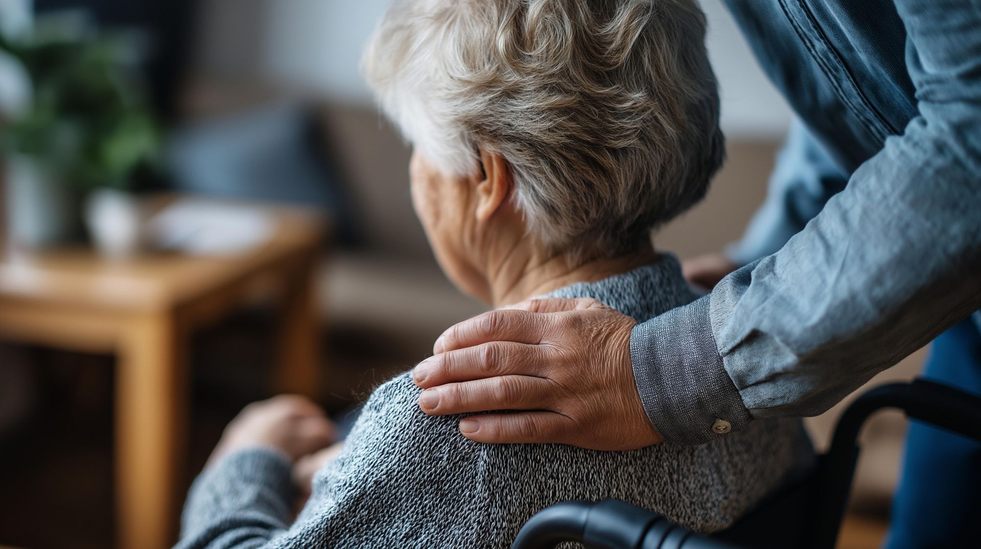 Hand resting on an elderly person’s shoulder in a cozy home setting